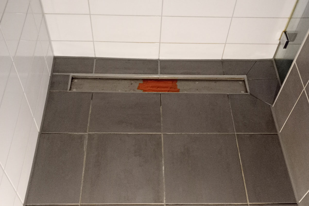 Douchegoot in een grijs betegelde douchecel