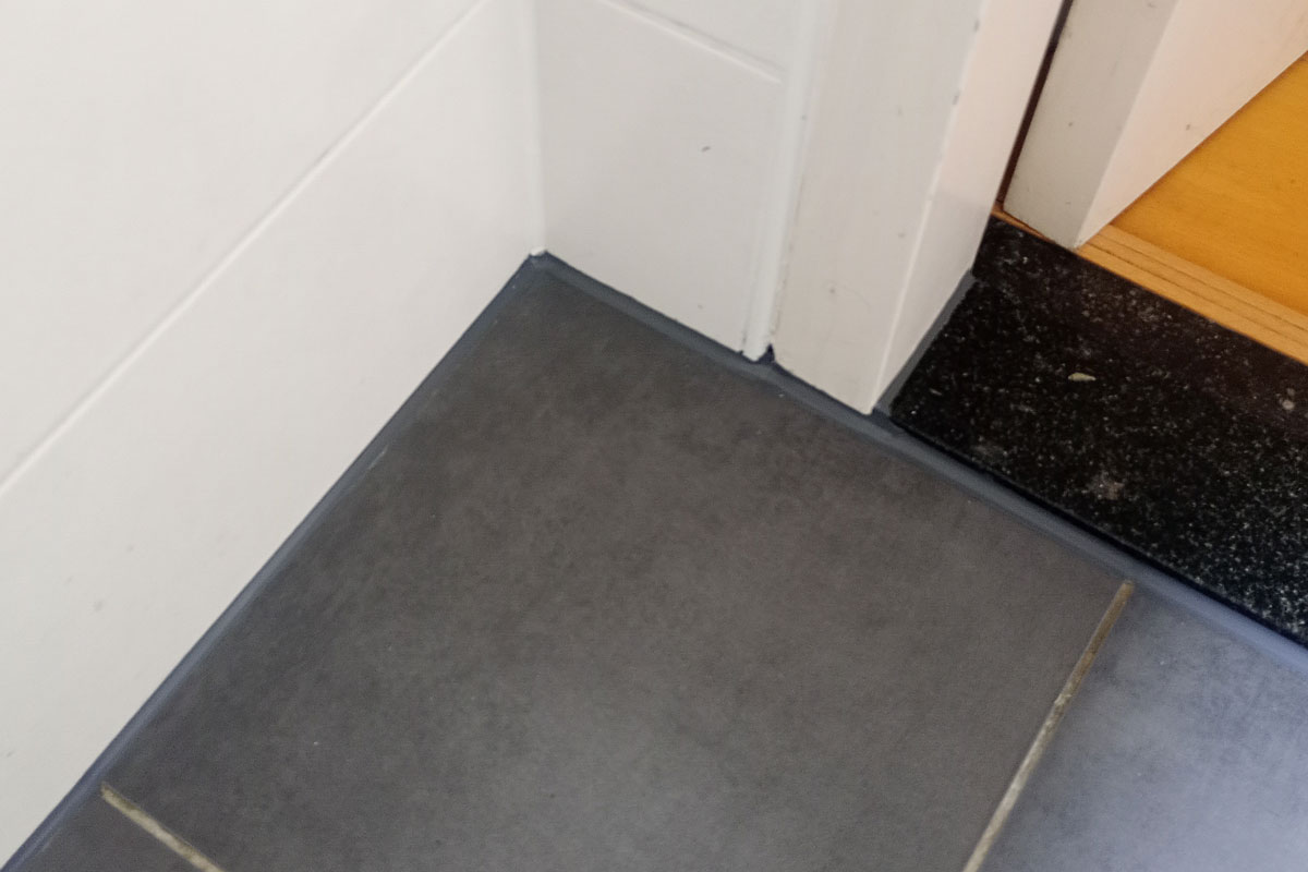 Kitrand tussen vloertegel en deurdorpel