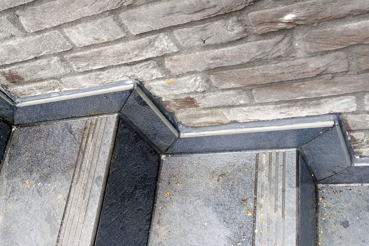 Betegelde buitentrap met plint, grijs afgekit tegen de bakstenen gevel
