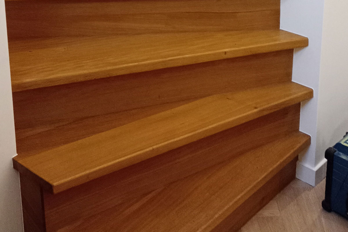 Eiken trap met treden en stootborden, afgekit langs de witte wand
